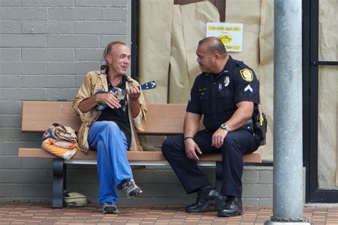 Homeless Man And Police Officer Sitting On A Bench Waikiki Beach Oahu