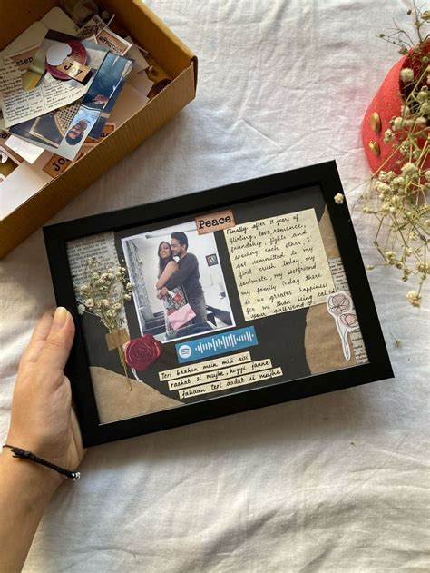 A Person Holding Up A Framed Photo In Front Of A Table With Flowers And