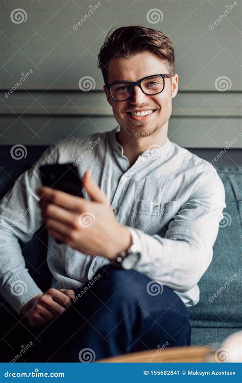 Smiling Man In Eyeglasses Holding A Smartphone At Cafe Stock Image