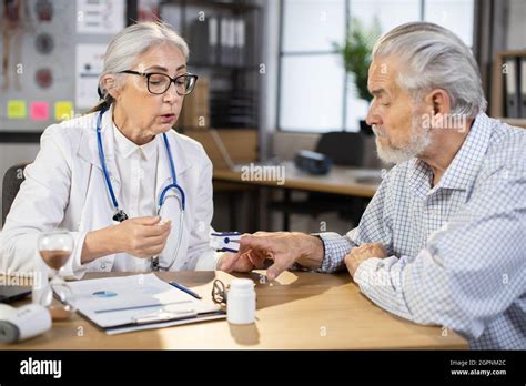 Femme mature médecin en lunettes et surveillance uniforme de la saturation des patients âgés de