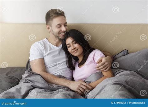 Loving Diverse Couple Hugging Lying In Bed Enjoying Weekend Stock Image