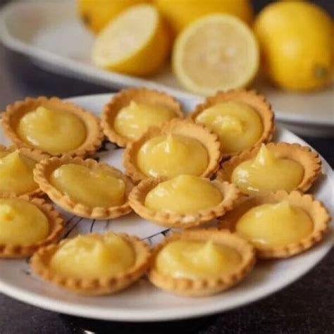 Lemon Tarts On A White Plate Next To Some Lemons