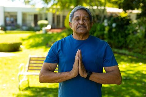 Hombre mayor birracial con los ojos cerrados meditando en posición de