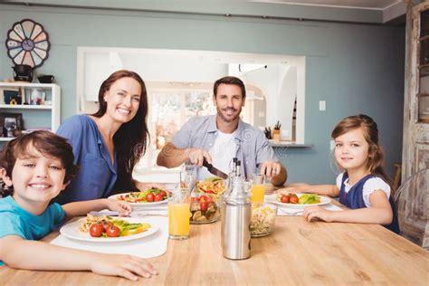 Retrato De La Familia Feliz Con La Comida En La Mesa De Comedor Imagen