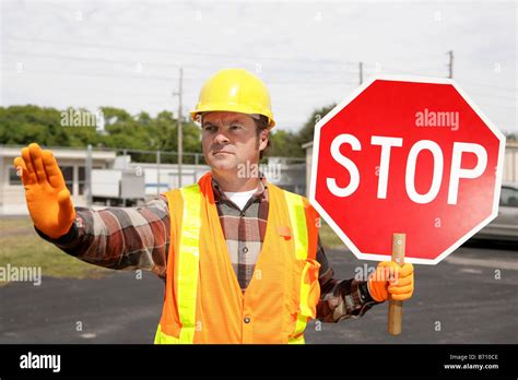 Construction Worker Holding Stop Sign On City Street Stock