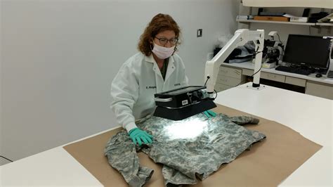 Army Cid Forensic Scientist Collects Evidence From Clothing In Lab