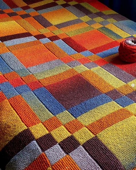 A Multicolored Crocheted Blanket With A Spool Of Yarn Next To It