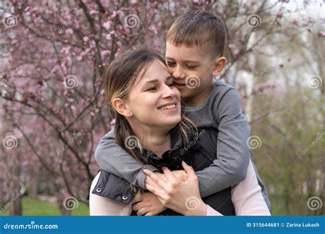 Happy Mom And Son Hugging Among Cherry Blossoms In Spring Stock Image