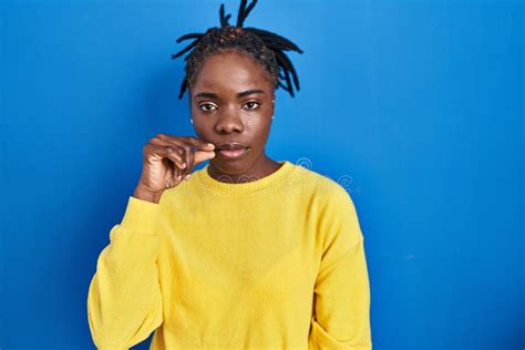 Beautiful Black Woman Standing Over Blue Background Mouth And Lips Shut As Zip With Fingers