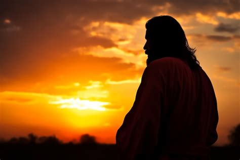 Un hombre con una túnica roja se para frente a una puesta de sol con la