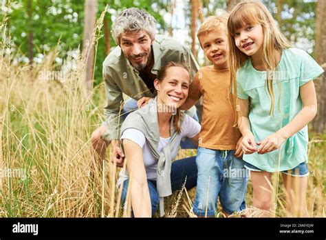 Portrait Of Happy Kids And Parents Exploring Forest Together In Summer