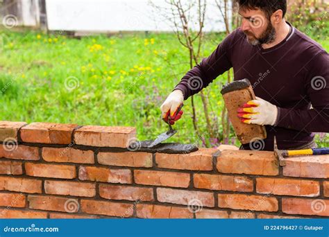 A Man Builds A Wall Of Bricks Lays A Brick On A Cement Sand Mortar