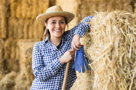 Female Farmer Posing In Barn Against The Backdrop Of Hay Bales Stock