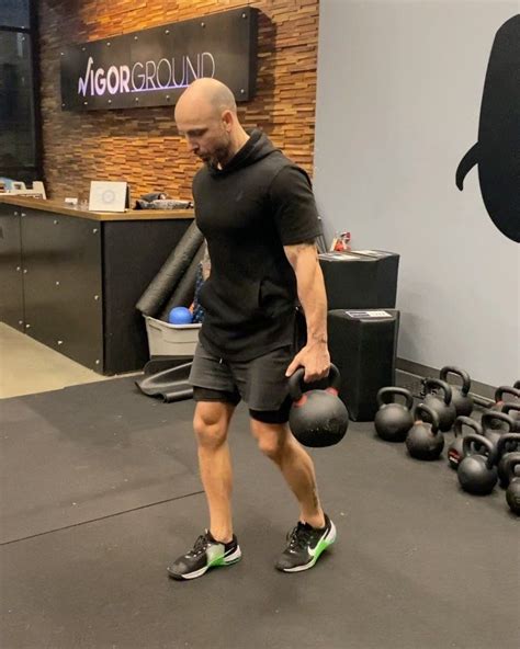 A Man Holding A Kettle While Walking Through A Gym Filled With Kettles