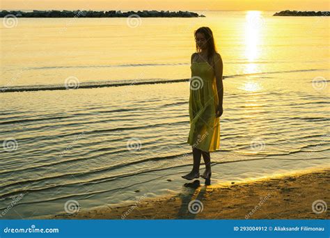 A Young Woman Walks Along The Beach At Sunrise And Shares Her