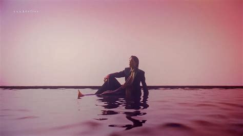 A Woman Is Sitting In The Water With Her Legs Crossed And Looking Off