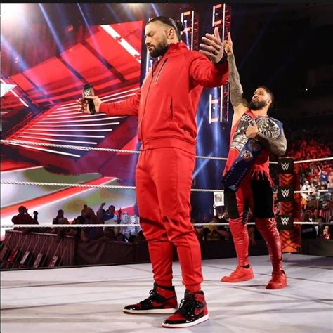 two men in red suits standing next to each other on a wrestling ring ...