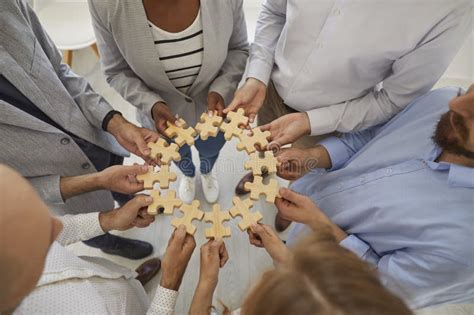 Team Of Business People Connecting Pieces Of Jigsaw Puzzle To Show