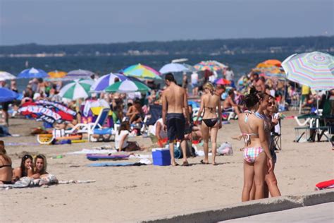 Many People Are On The Beach With Umbrellas And Sunbathers In The Background