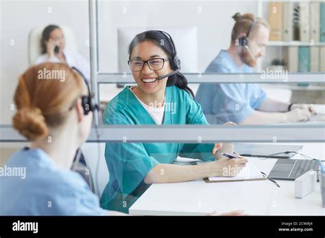 Two Operators In Headphones Talking And Laughing At The Table During