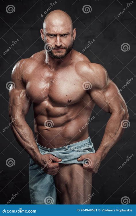 Serious Guy With Naked Torso Pulls His Shorts Showing His Leg In Studio