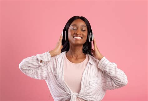 Relaxed Black Woman In Headphones Enjoying Good Song And Smiling With