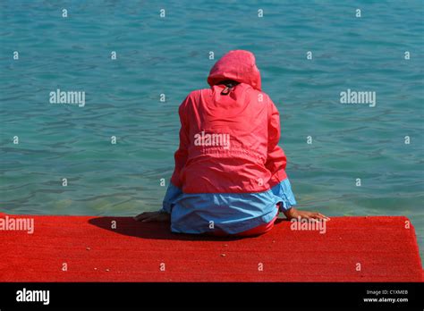 Mujer sentada de nuevo a nosotros en el dock en traje de baño para