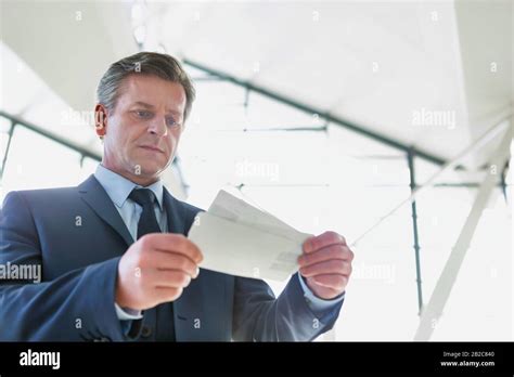 Mature Businessman Looking At His Boarding Pass In Airport Stock Photo
