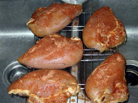 Chicken Breasts Seasoned With Dry Rub Resting On A Wire Grate Over The