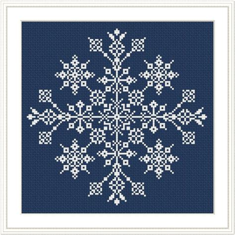 A Cross Stitch Snowflake Pattern In Blue And White On A Dark Blue