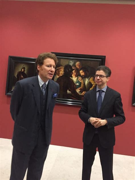 two men standing next to each other in front of paintings on the wall ...