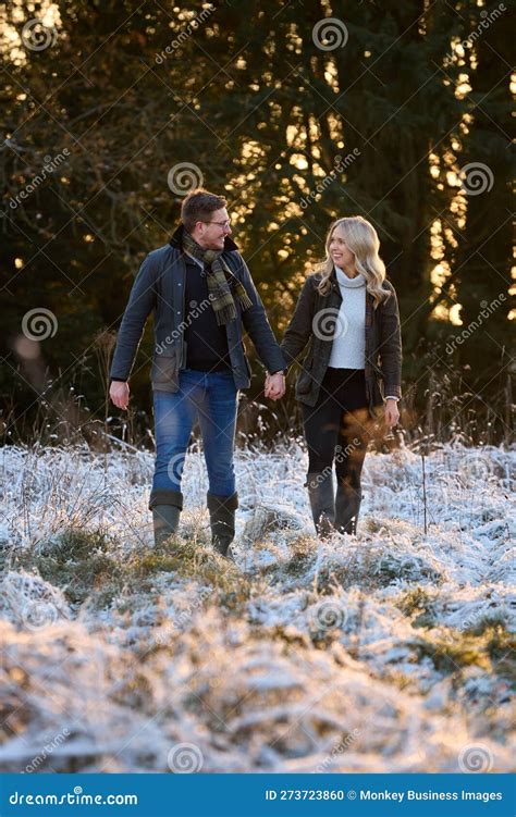 Loving Couple Holding Hands On Snowy Walk In Winter Countryside Stock