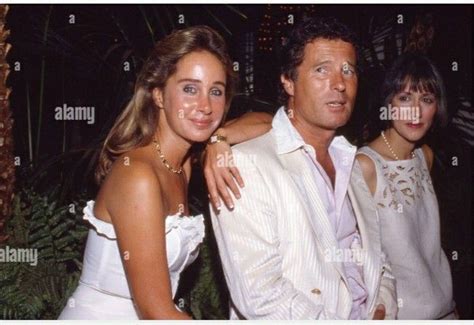 Two Women And A Man Posing For The Camera In Front Of Palm Trees