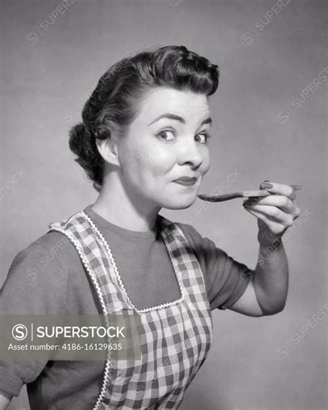 1950s Smiling Woman Housewife Wearing Checkered Apron Looking At Camera With Raised Eyebrows