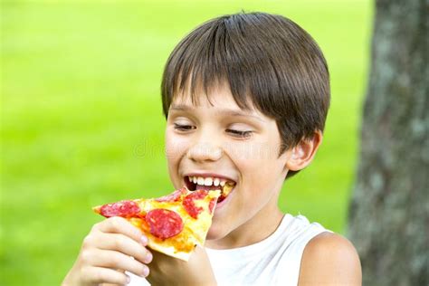 The boy is eating pizza stock photo. Image of portion - 97603864