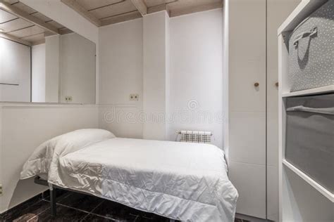 A Small Bedroom With White Walls With Wooden Coffered Ceiling A Single