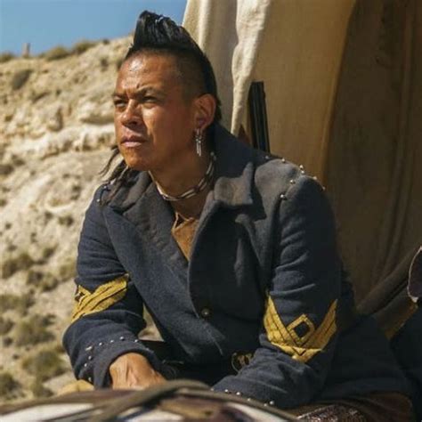 A Man Sitting On Top Of A Chair Next To A Desert Area With Mountains In