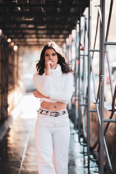 Woman In White Long Sleeve Shirt And Blue Denim Jeans Standing On Bridge During Daytime Photo