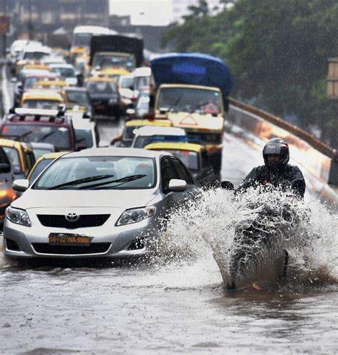 People Wade Through A Flooded Street After Heavy Downpour In Mumbai