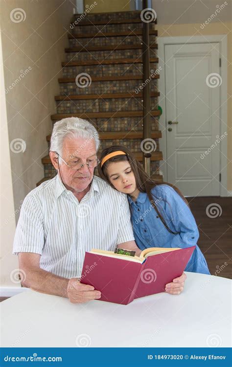 Grandfather And Granddaughter Read A Book In The House Stock Photo