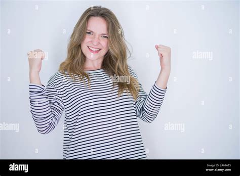 Belle fille blonde aux yeux bleus portant sur pull rayé blanc fond isolé célébrant surpris et
