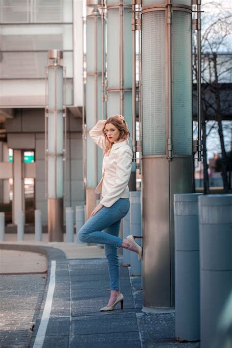 Woman In White Long Sleeve Shirt And Blue Denim Jeans Standing With Bicycle On Road · Free Stock