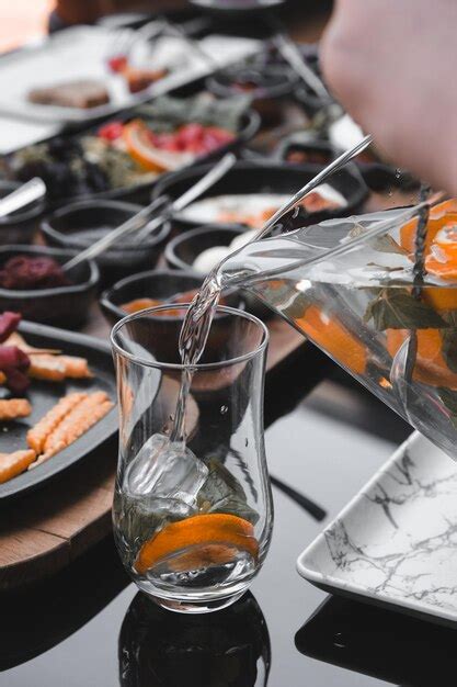 Premium Photo A Person Pouring Water Into A Glass With Orange Slices