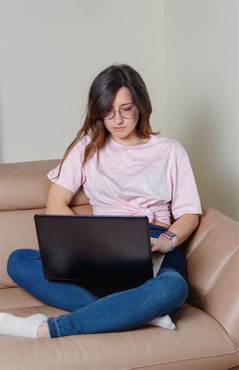 Young Women Working With Laptop While Sitting On The Sofa At Home Stock