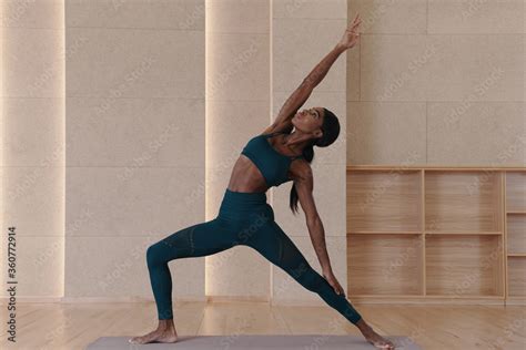 Young Black Woman Practicing Yoga Doing Exalted Crescent Lunge Twist On The Knee Exercise