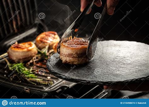 Cooking Beef Steak On Grill By Chef Hands On Black Background For Copy