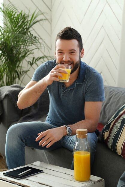 Jovem bonito bebendo suco de laranja em casa Foto Grátis