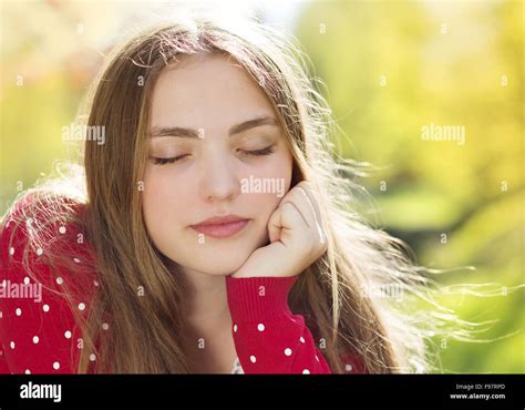 Portrait Of Beautiful Girl In Red Cardigan Daydreaming In Green Prak