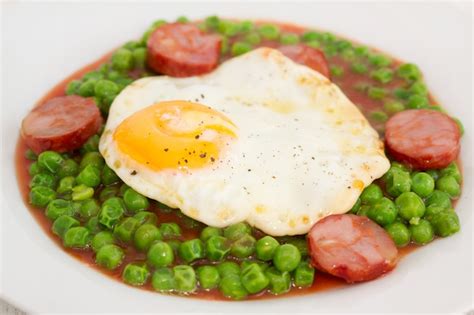 Guisantes Con Chorizo Ahumado Y Huevo Frito En Plato Foto Premium