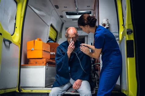 Man In A Medical Uniform Sitting In The Ambulance Car At Night Stock